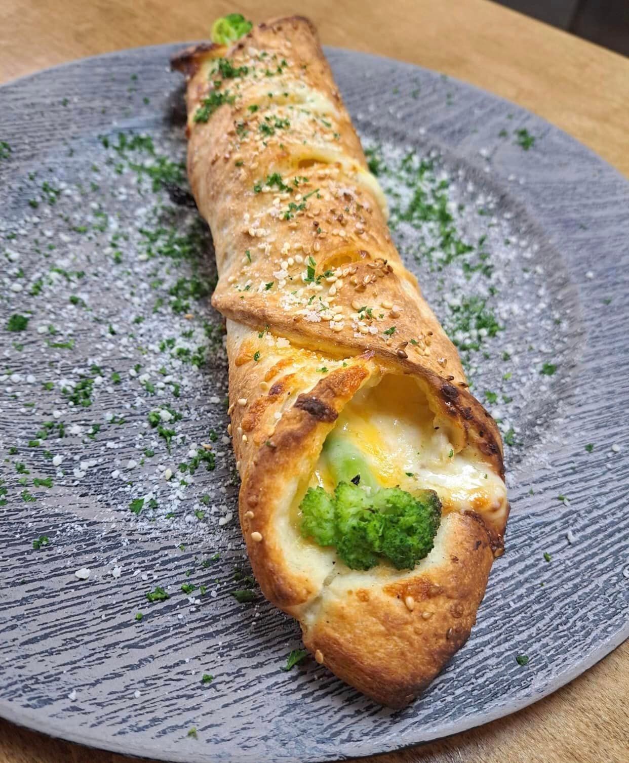 A close up of a pizza with broccoli and cheese on a plate.