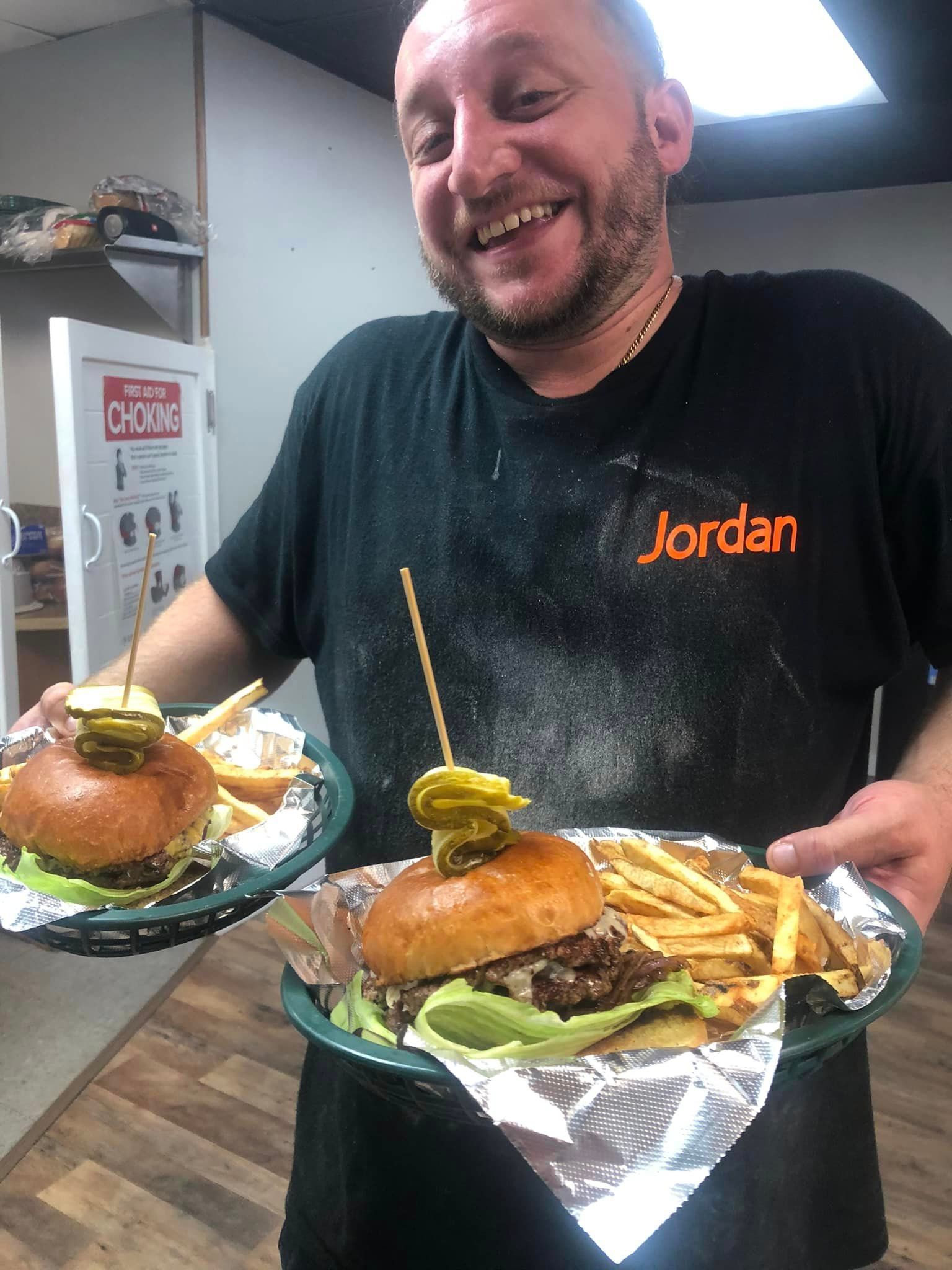 A man in a jordan shirt is holding two plates of food.