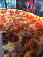 A pizza with a slice taken out of it that says meat mania