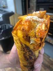 A person is holding a tortilla cone with meat and sauce on it.