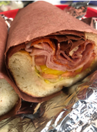 A close up of a sandwich wrapped in brown paper