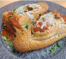 Two meatball subs with sauce and cheese on a plate.