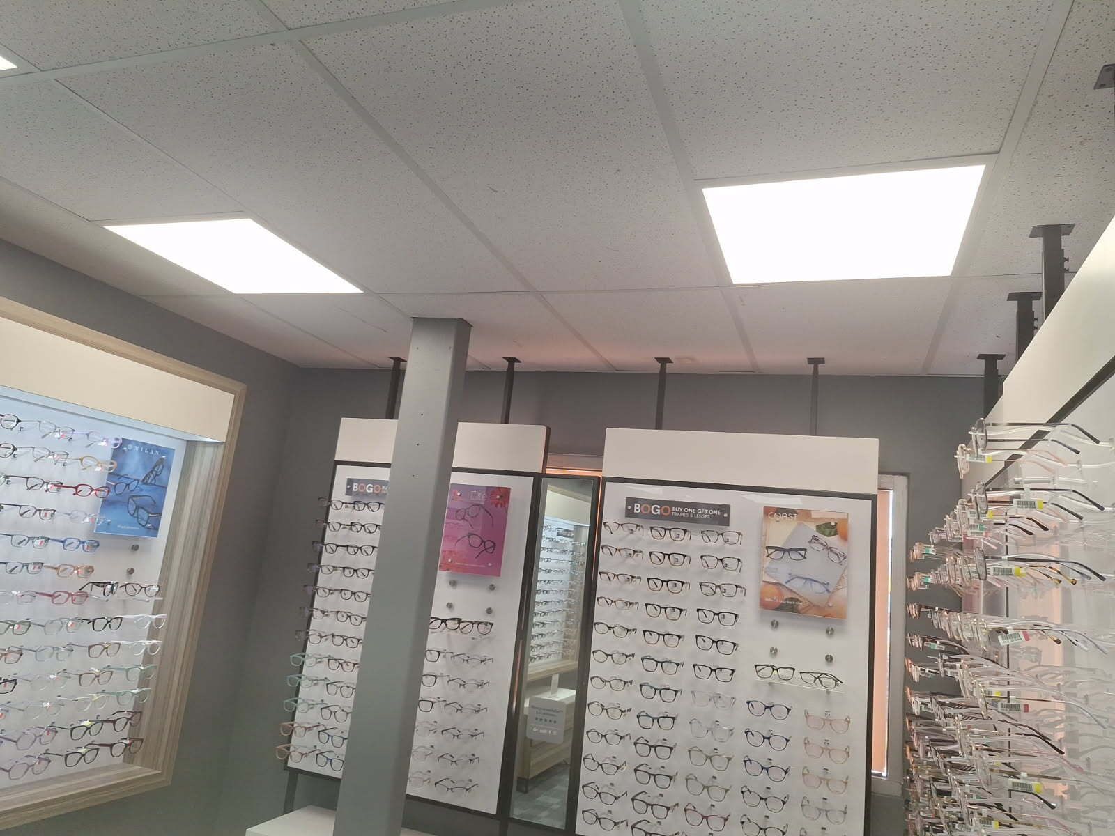 An optical shop interior with eyeglasses displays and overhead lighting.