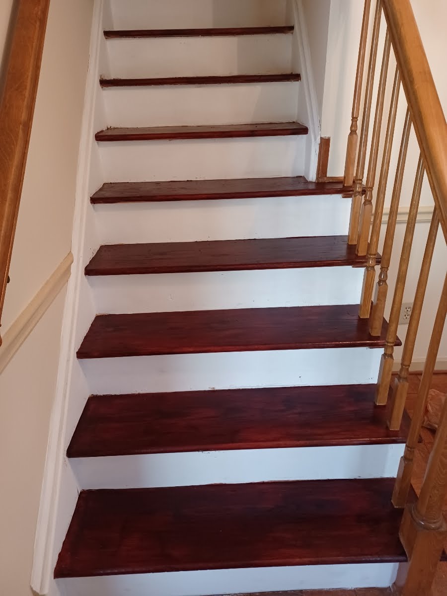 Wooden staircase with stained treads and white risers, leading upwards.