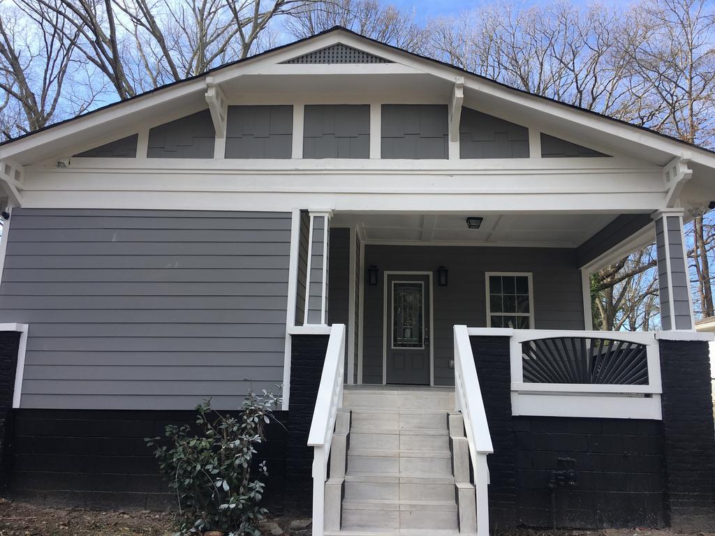 Gray and white Craftsman-style house with porch, steps, and black accents.