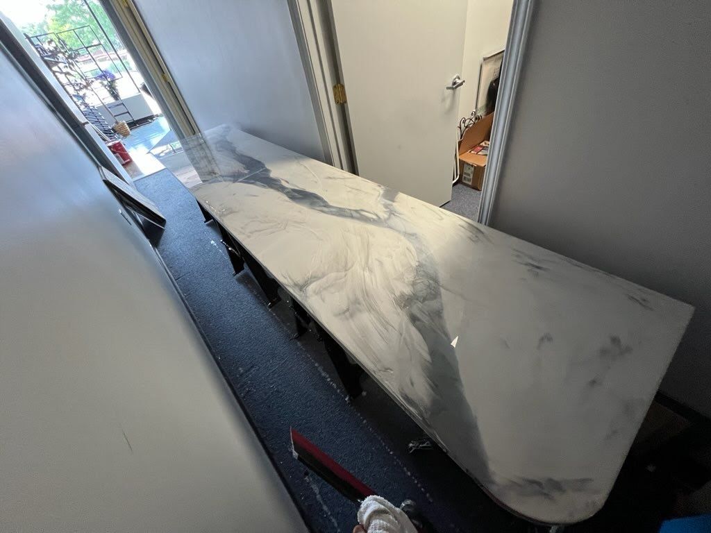 Long, marble-looking countertop extending from a doorway. Dark flooring, white walls, open door.