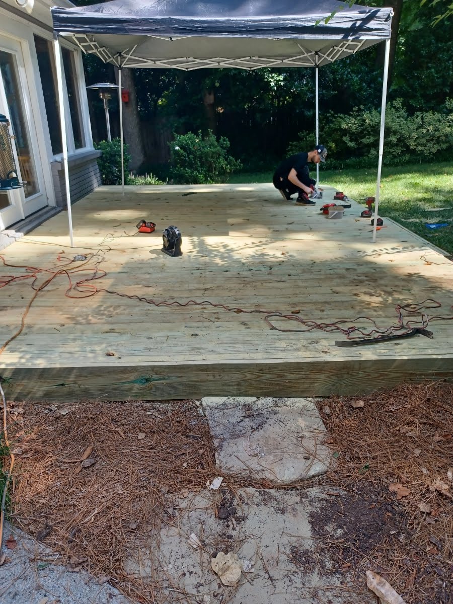 Person on a deck under a canopy, working on the deck construction.