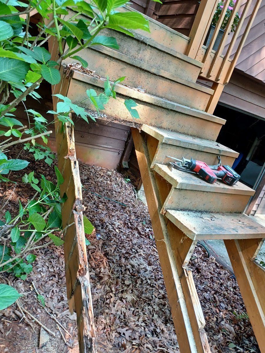 Wooden outdoor staircase under repair, with tools visible.  Debris and foliage surround.
