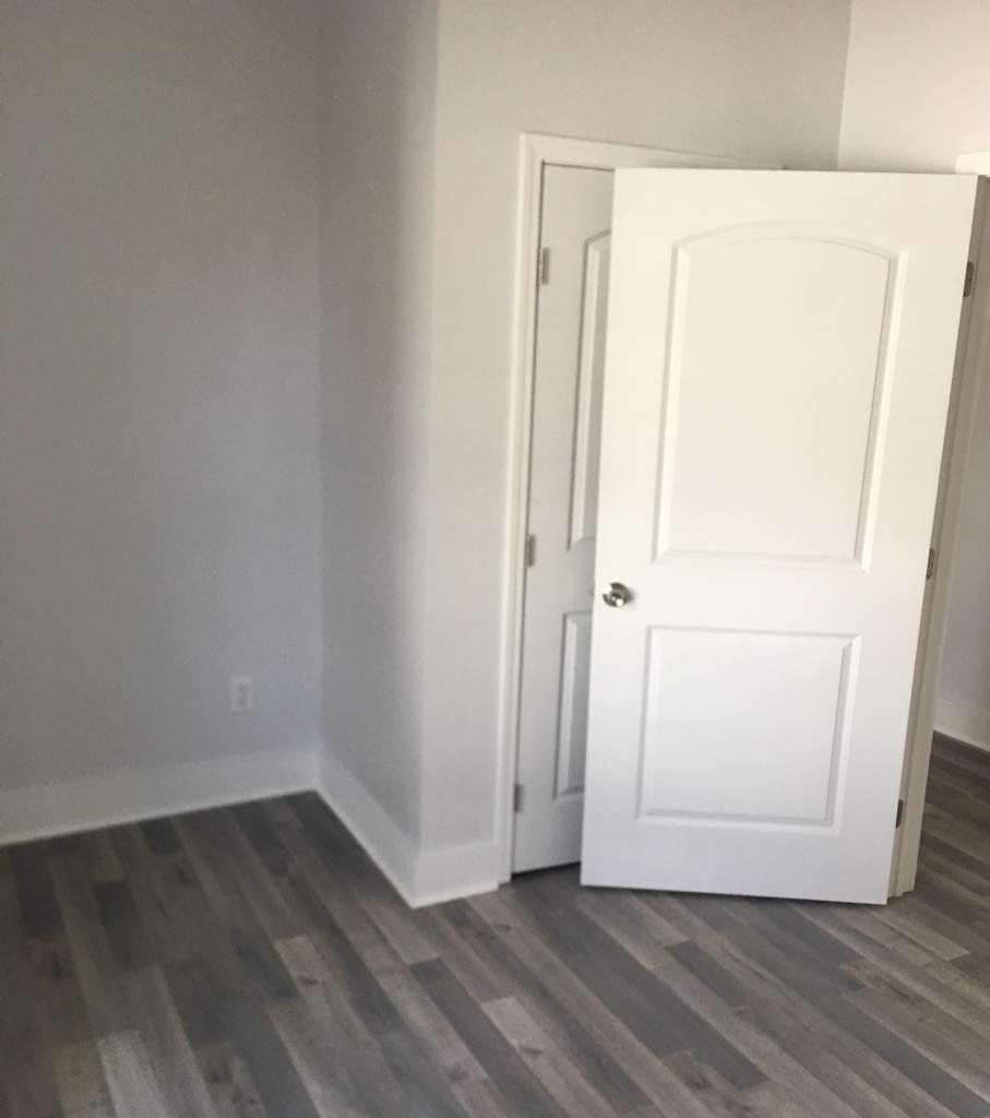 Interior room with gray walls and wood-look flooring. Two white doors are visible, one open.