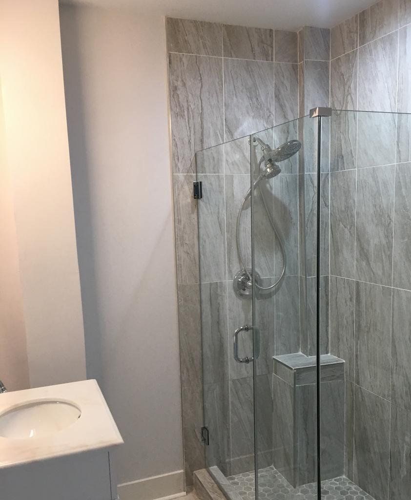Bathroom with tiled shower, glass door, and white vanity with sink.