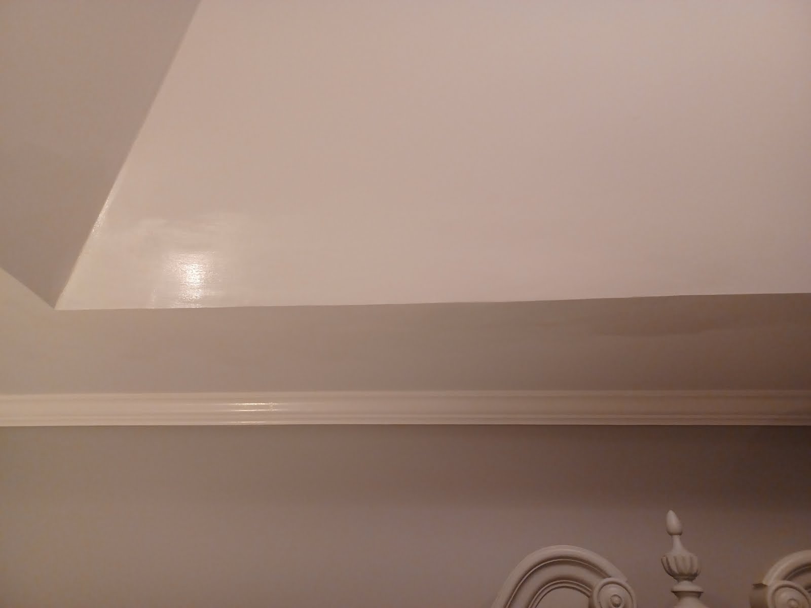 White ceiling with trim and a partial wall, lit room.