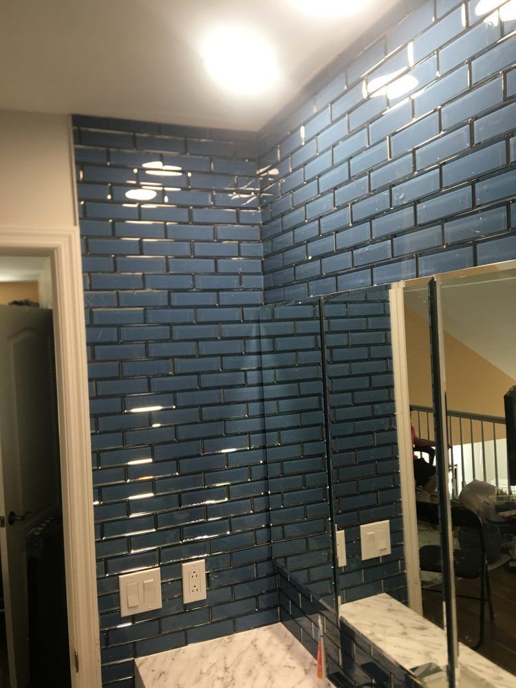 Blue tile wall with a partially visible mirror and light fixtures.