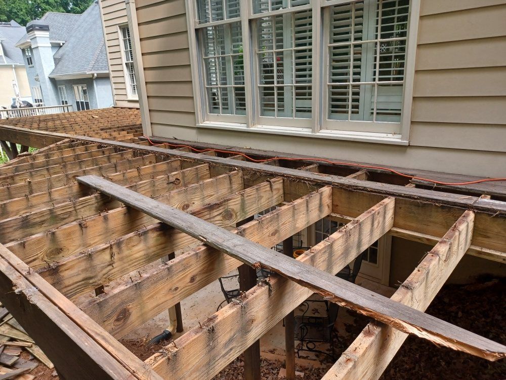 Partially dismantled wooden deck next to a house with an open area beneath the deck boards.