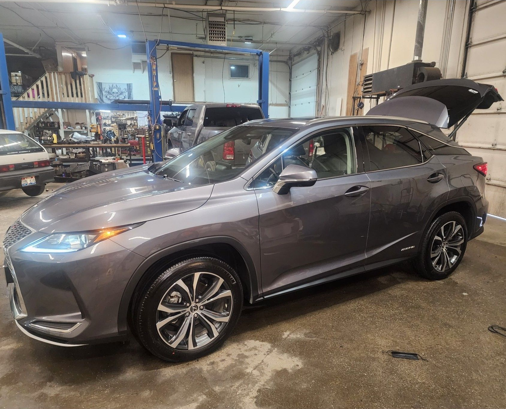 Gray SUV in a garage with its hood open on a service lift floor