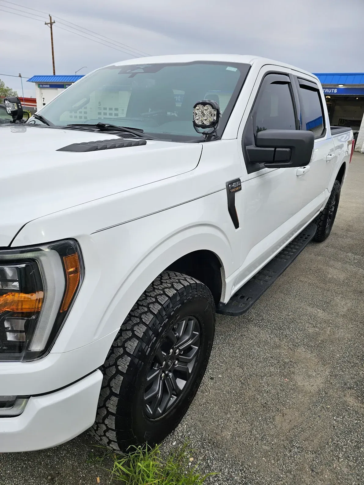 White pickup truck parked on a gravel lot, shown from the front side.
