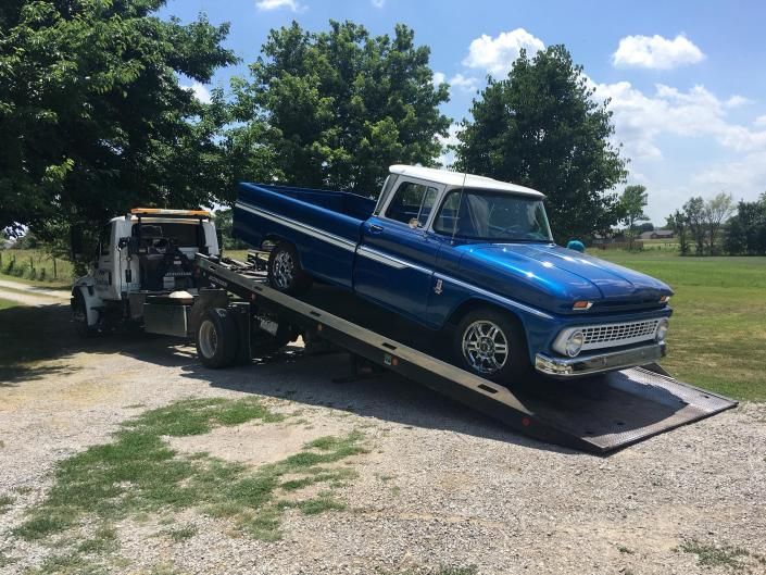 Blue and white classic pickup truck on a tow truck, outdoors.
