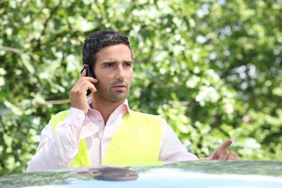 A man in a yellow vest is talking on a cell phone.