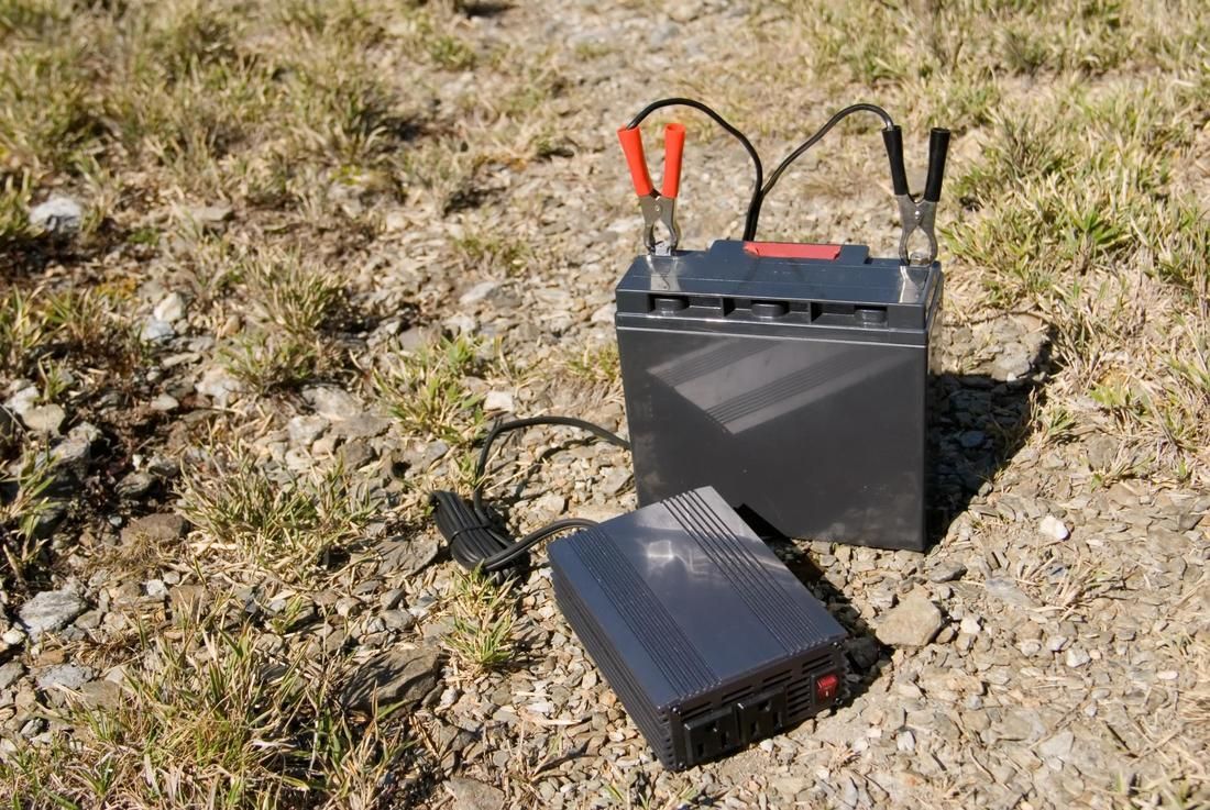 A battery is sitting on the ground next to a power supply.