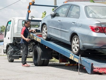 A man is loading a car onto a tow truck.