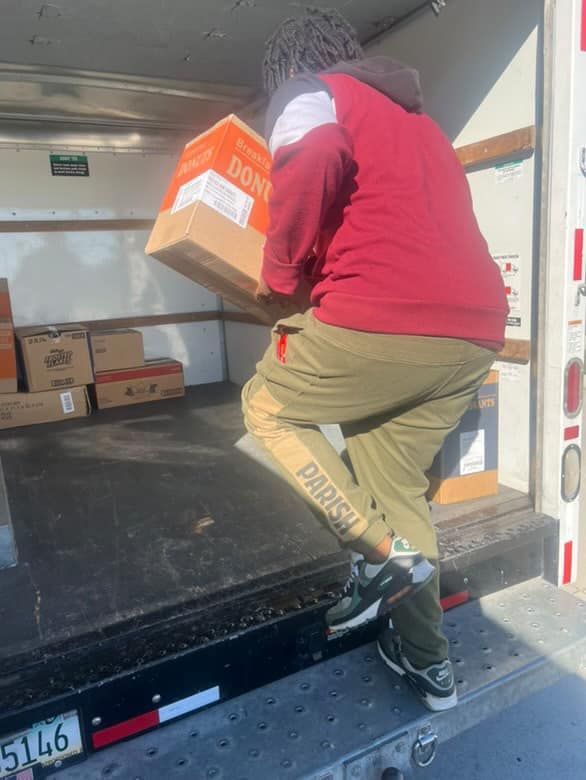 A man in a red shirt is carrying a box in the back of a truck.