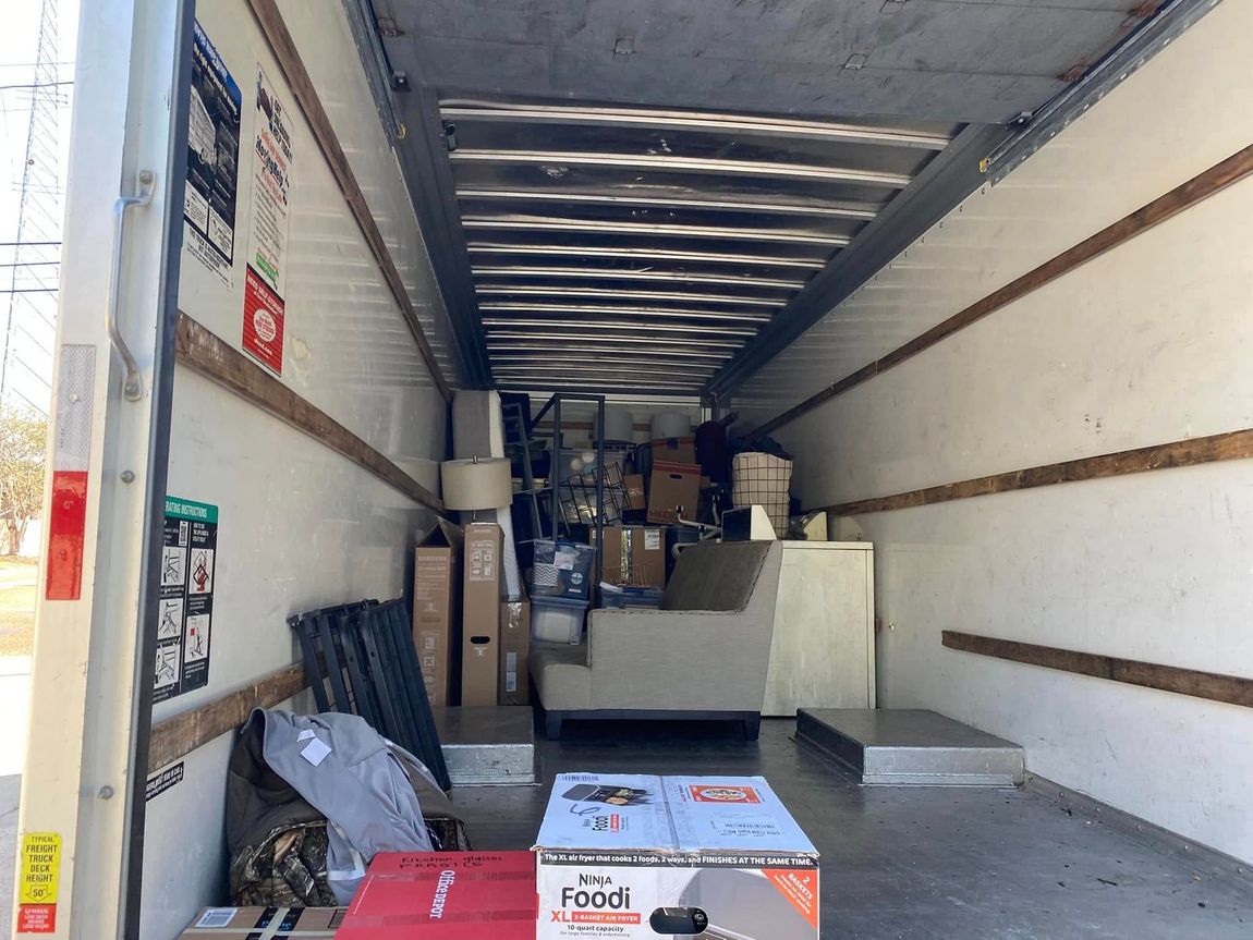 The inside of a moving truck filled with furniture and boxes.