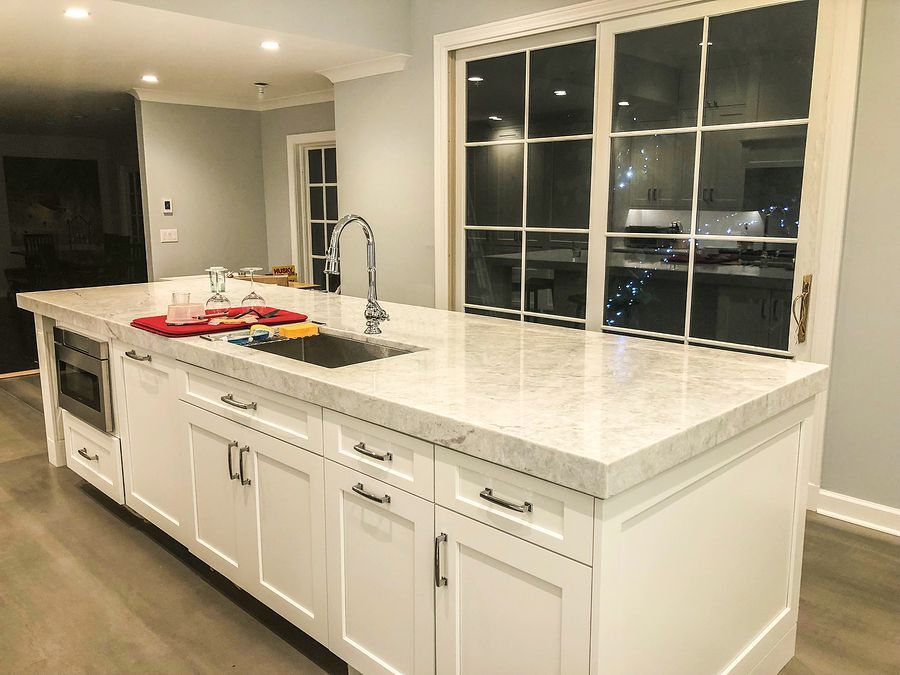 A kitchen with white cabinets and marble counter tops