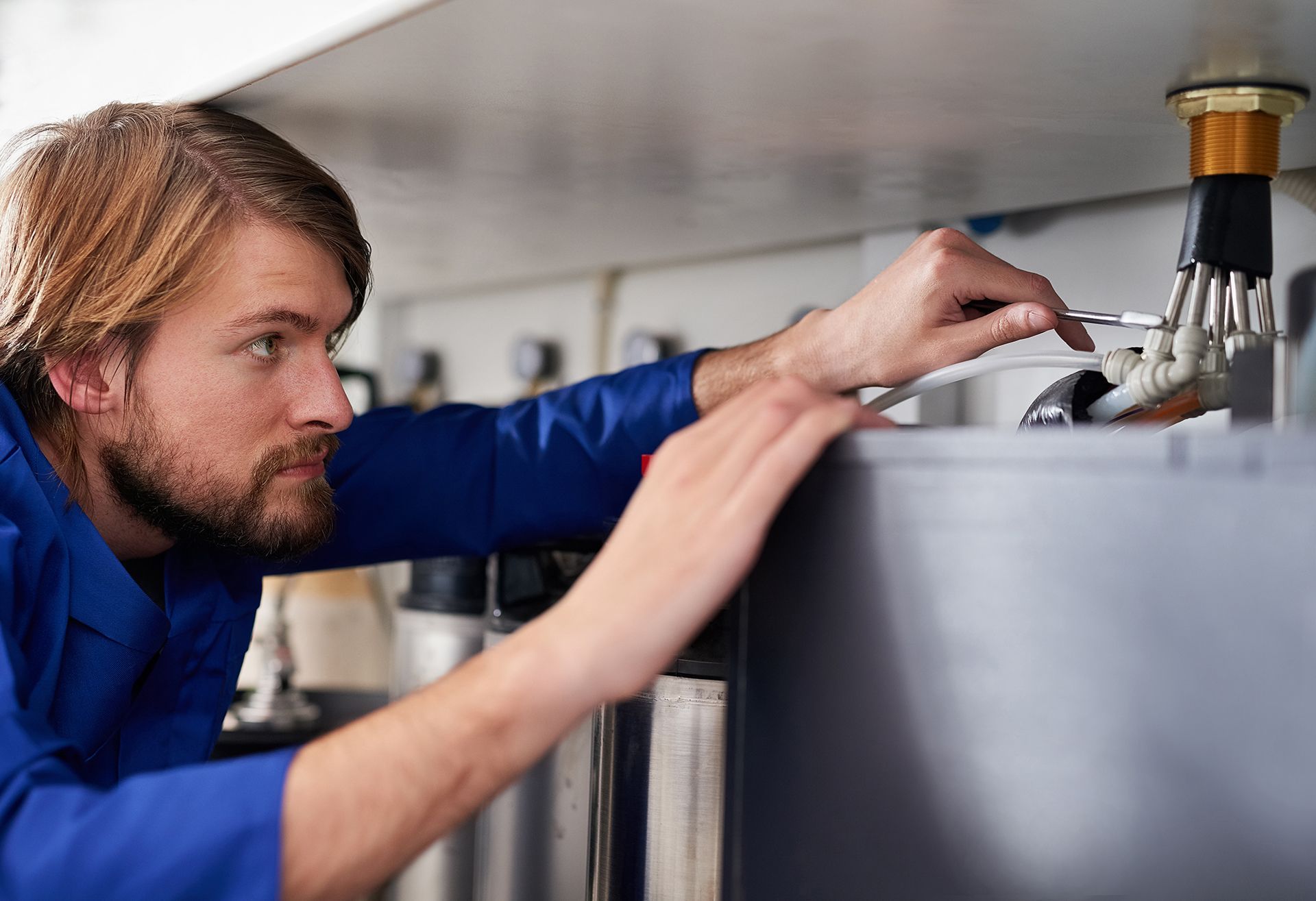 A man in a blue shirt is working on a sink