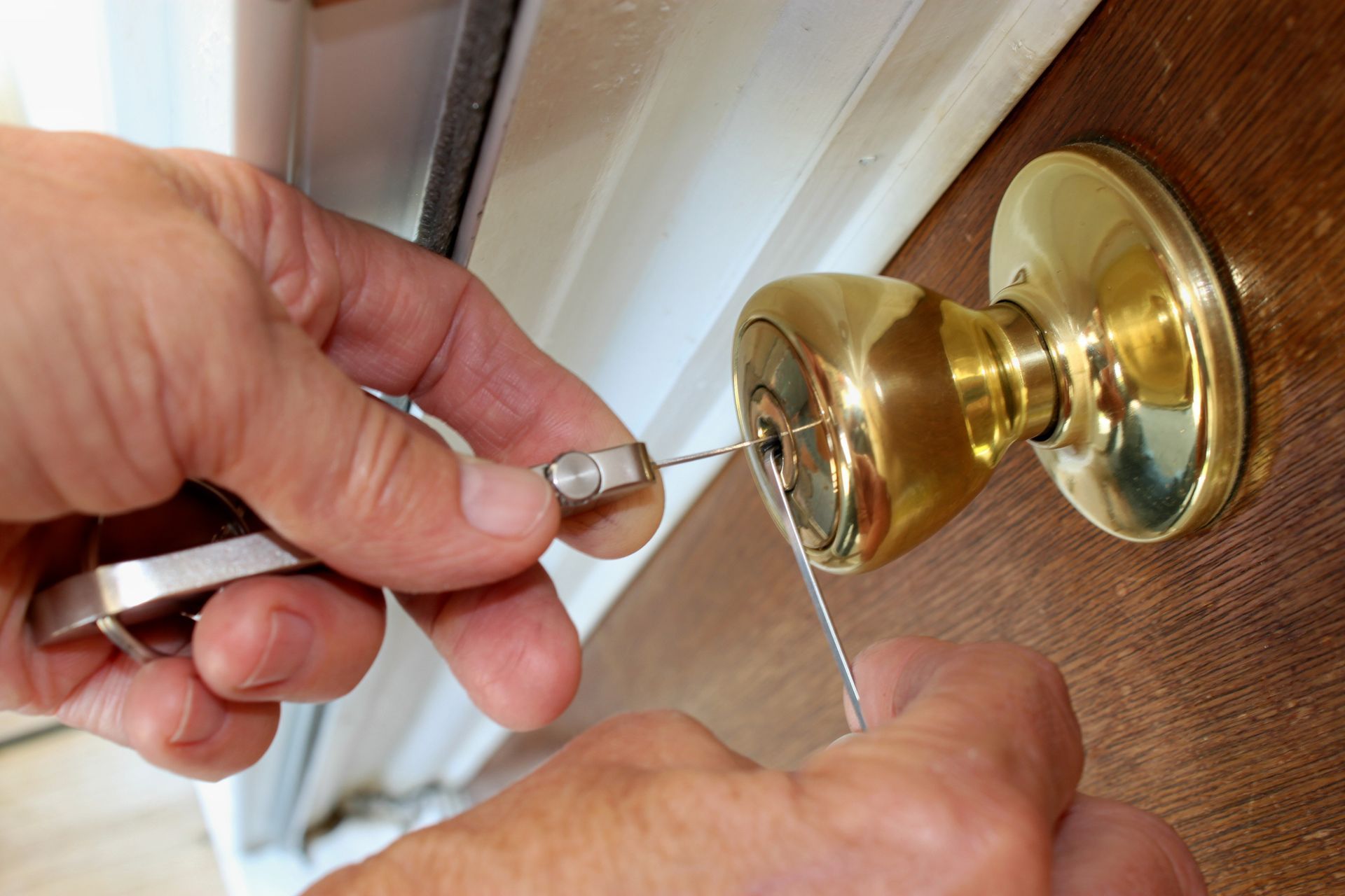 A person is fixing a door knob with a screwdriver.