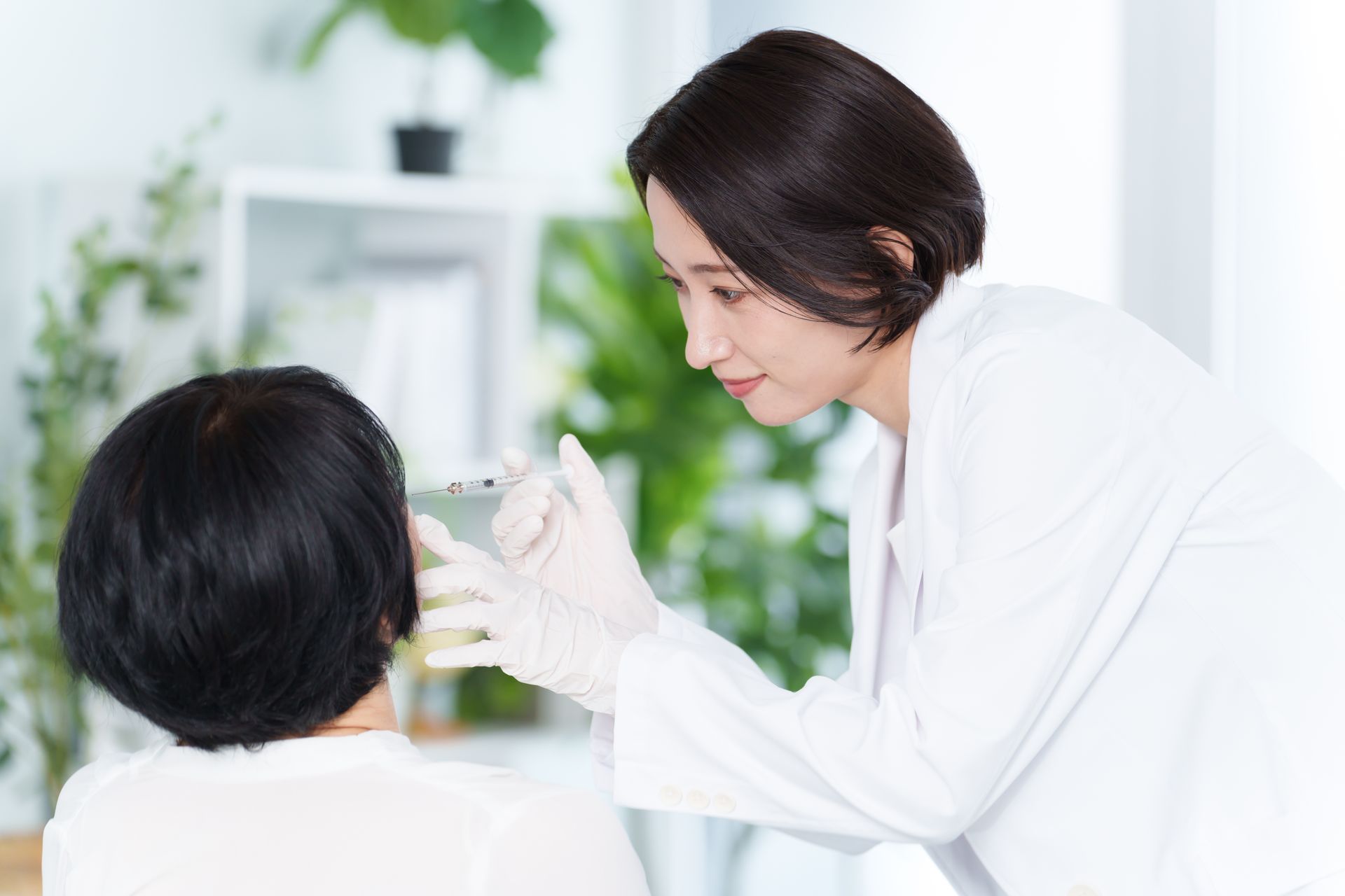 A female doctor is examining a patient 's face with a magnifying glass.
