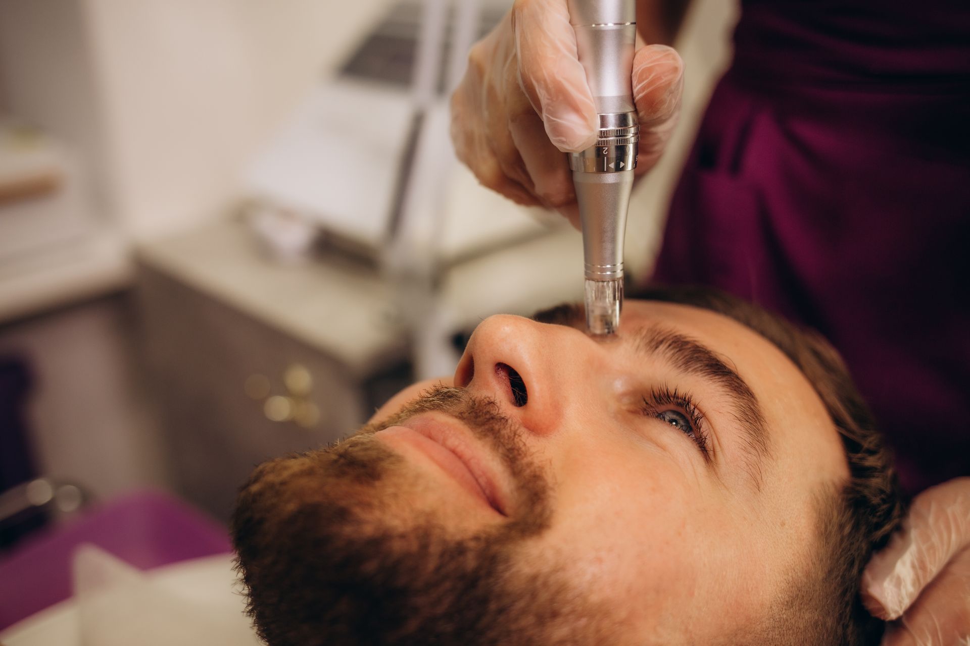 Man receiving a facial treatment with a skin needling device.