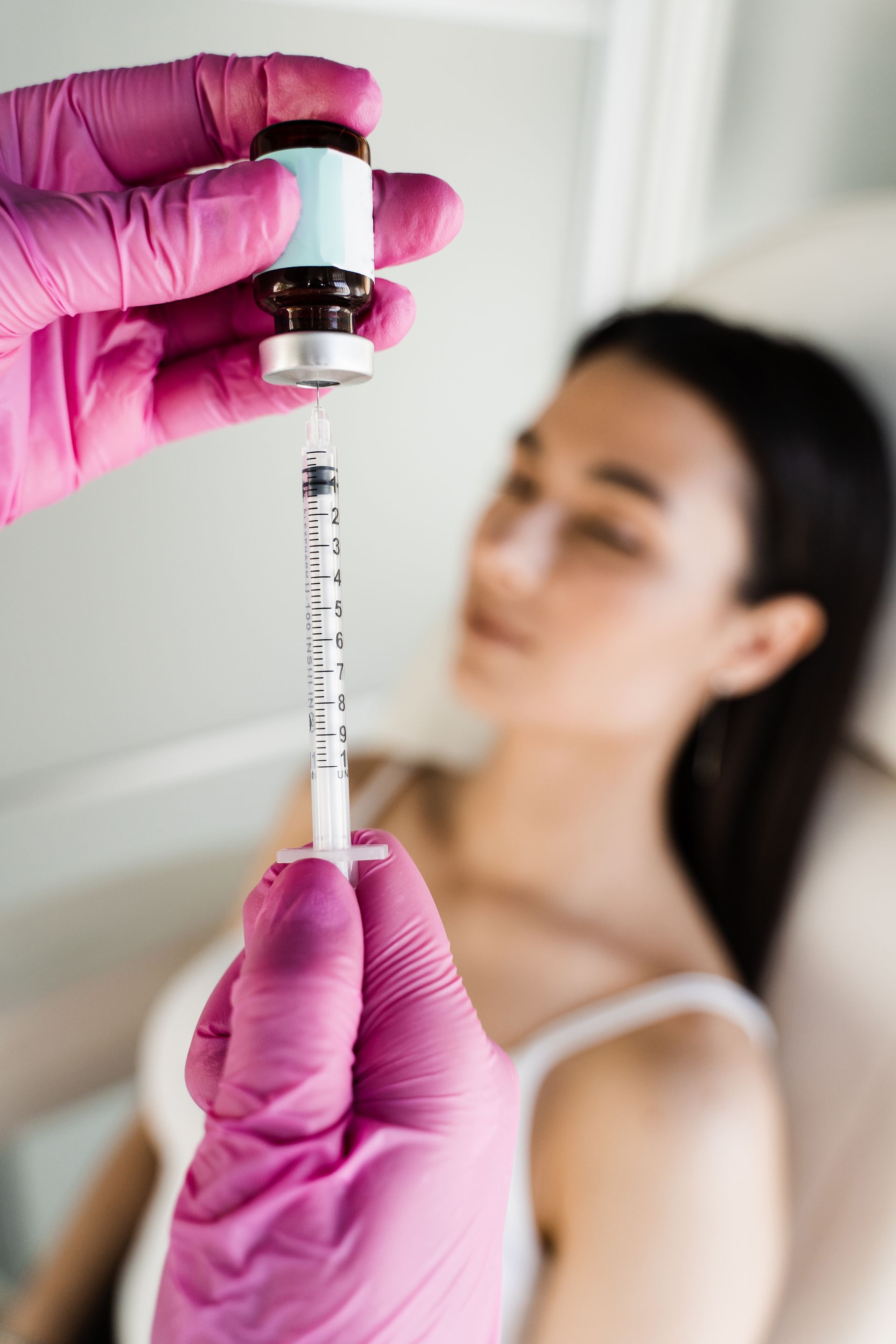 A person in a clinic setting prepares an injection with a syringe.