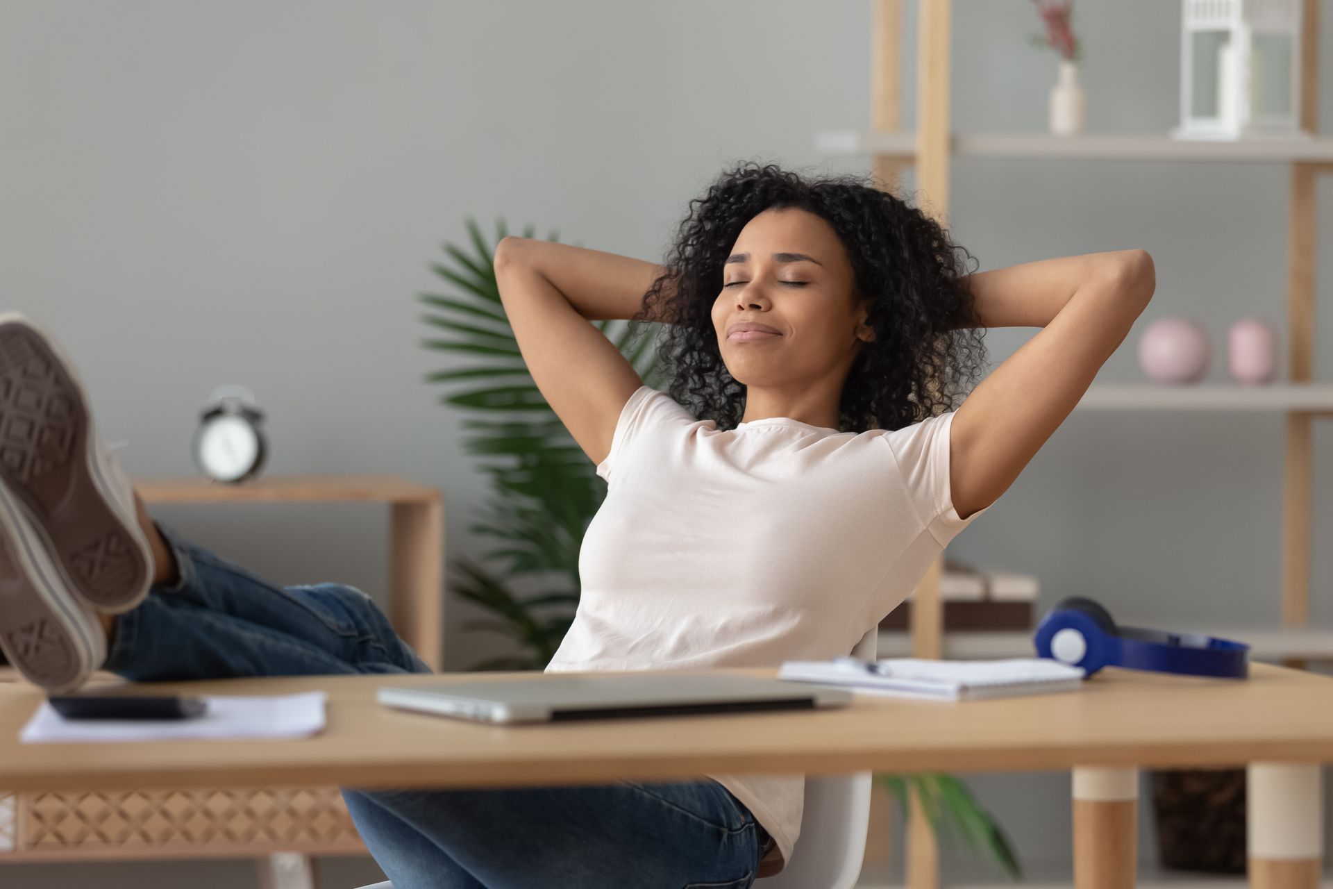 Woman relaxing at desk with feet up, eyes closed.