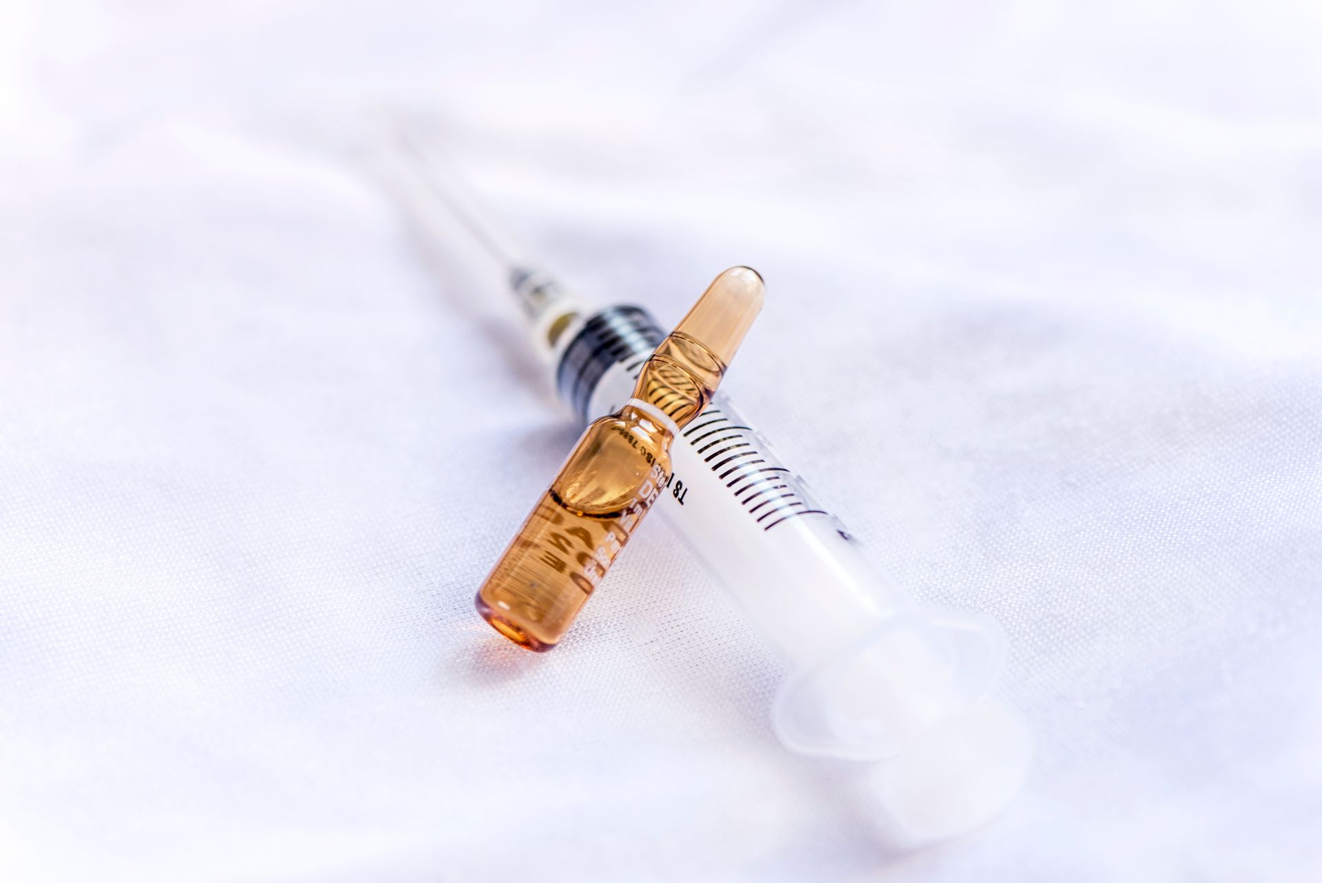 Syringe and brown ampule on a white cloth, suggesting medical treatment.