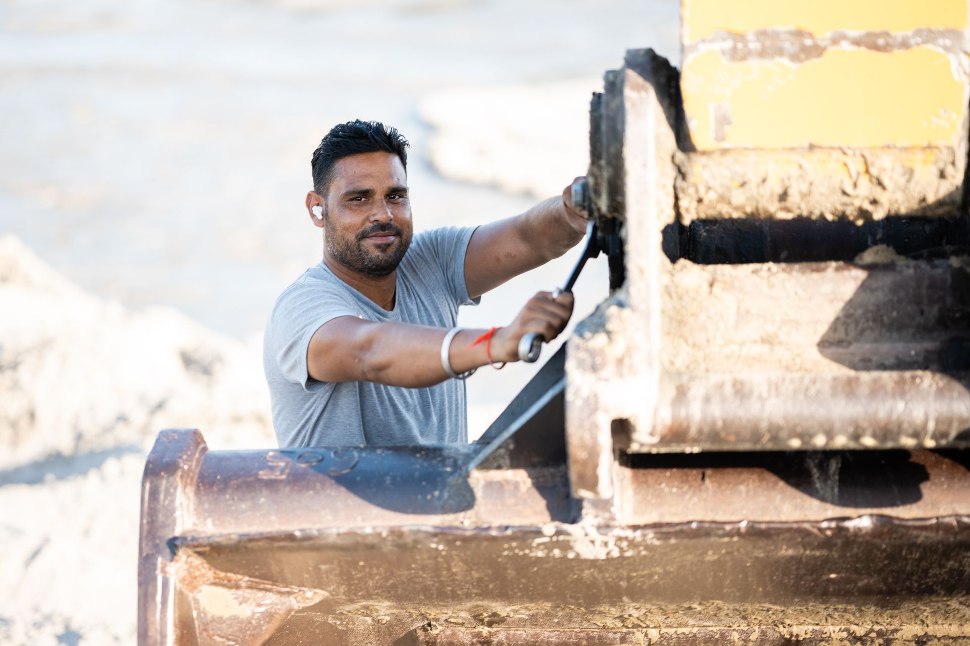 Commercial earthmoving contractors operating heavy excavator as worker talks on phone at jobsite. Commercial earthmoving contractors operating heavy excavator as worker talks on phone at jobsite.