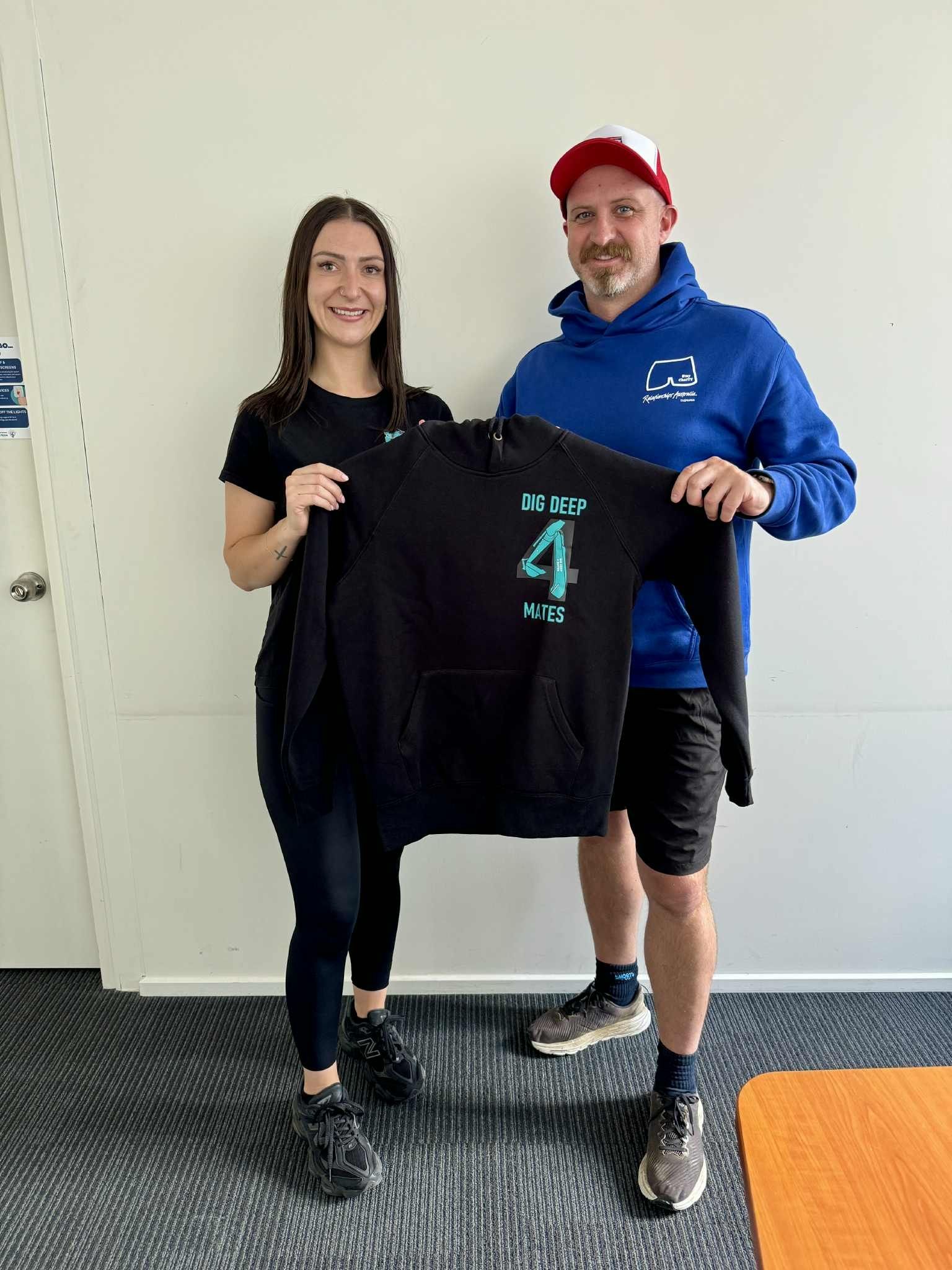Woman and man holding a black hoodie with turquoise 