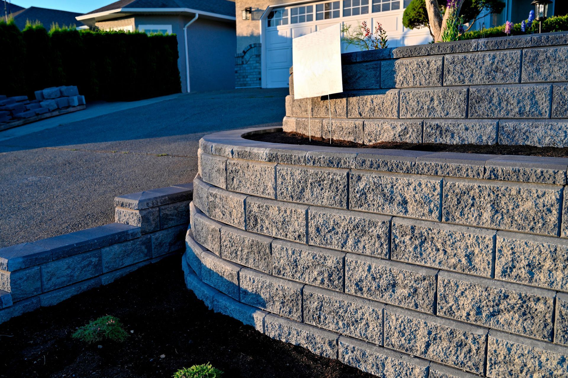 Tiered concrete retaining wall near driveway helps manage slope and prevent soil erosion.