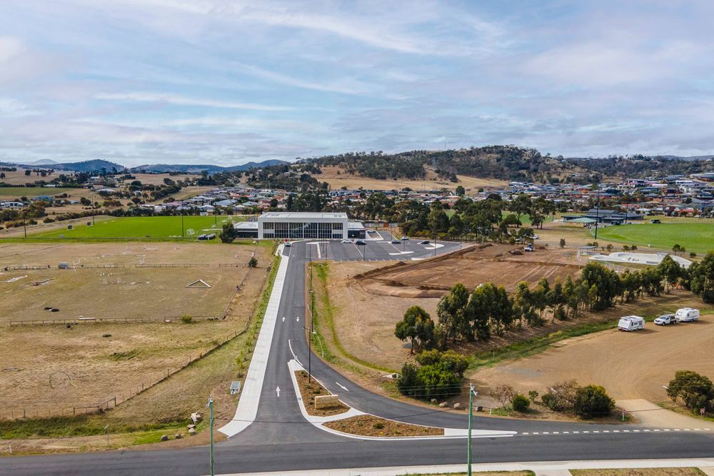 An aerial view shows a new road leading to a modern building in a rural area.