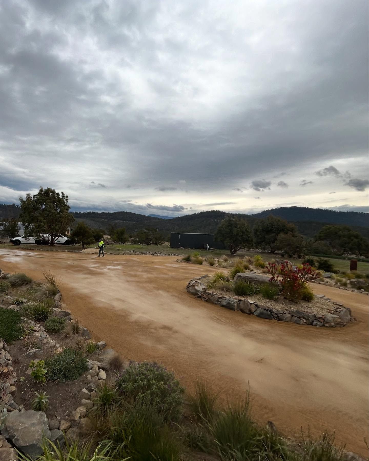 Dirt road and landscape under cloudy sky. 
