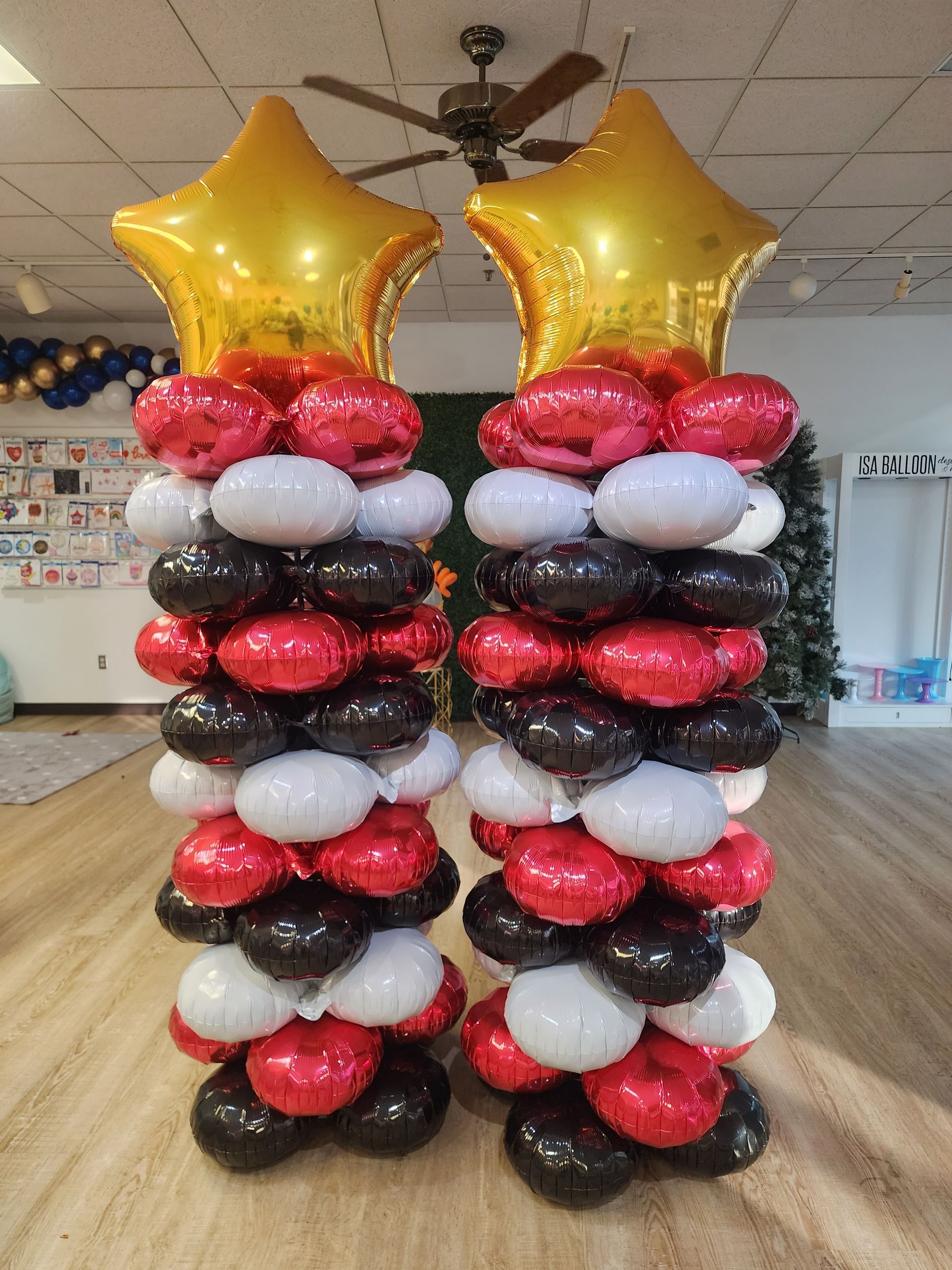 Two columns made of red , black and white balloons with gold stars.