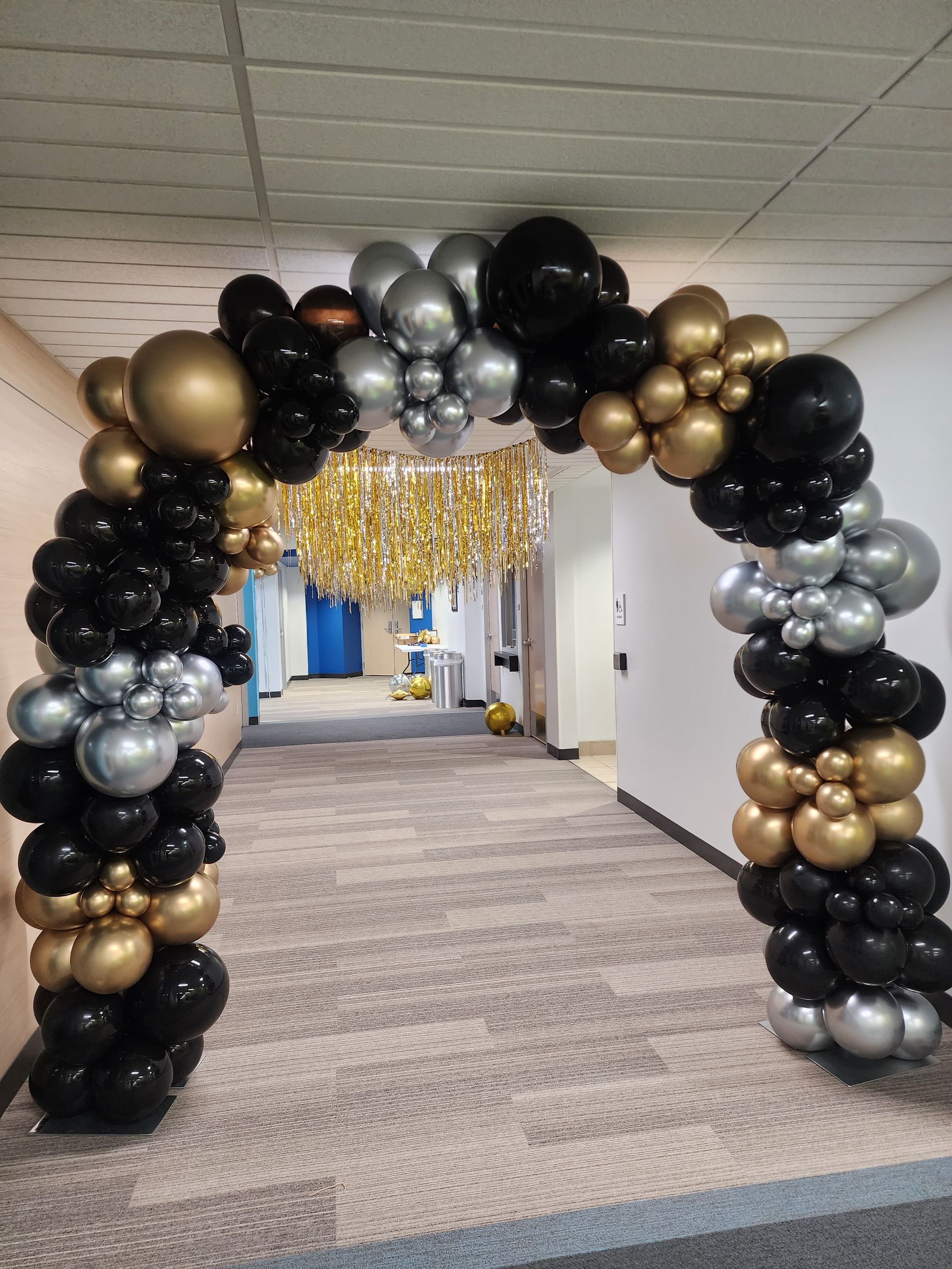 A hallway decorated with black , gold and silver balloons