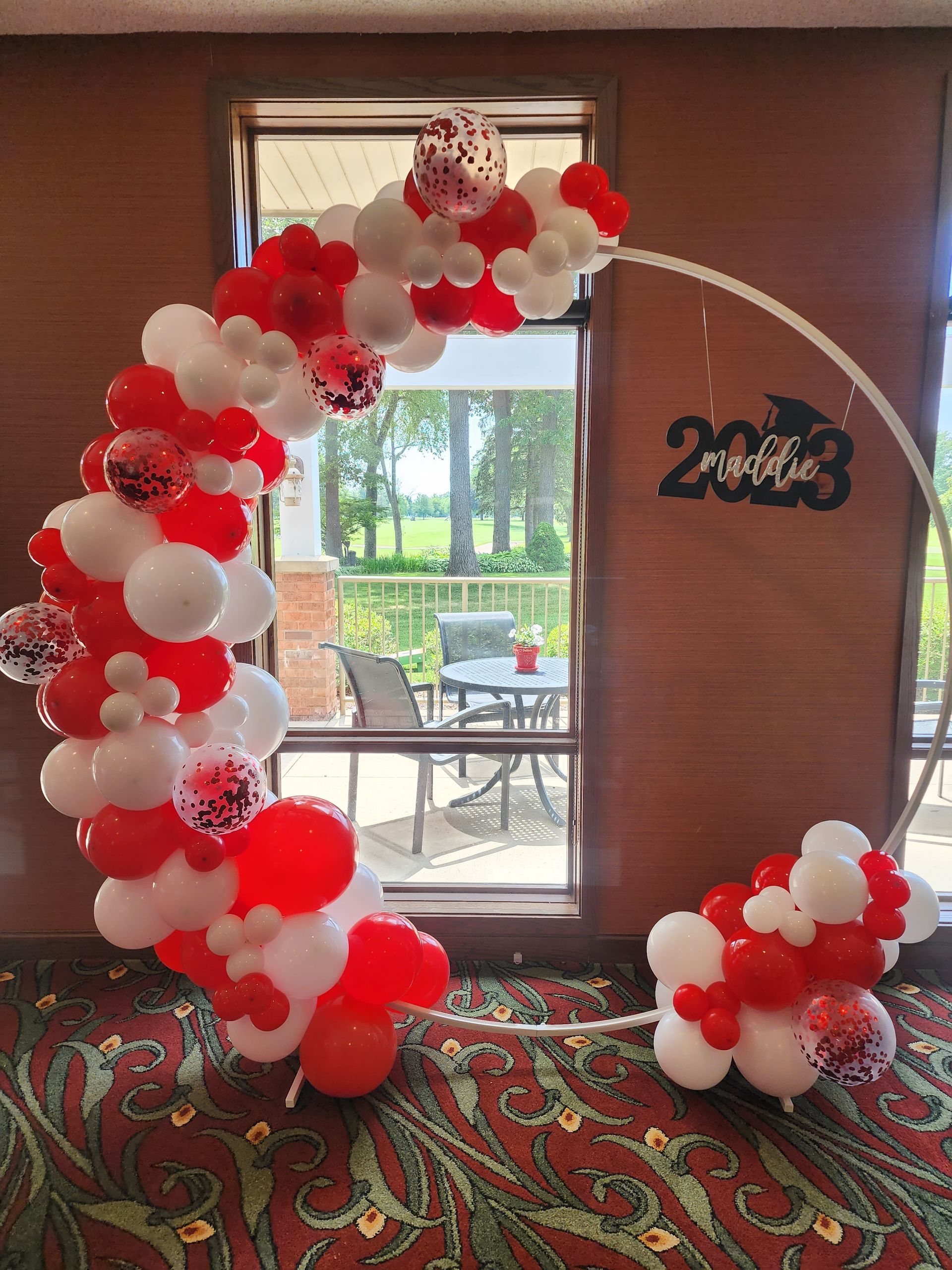 A room decorated with red and white balloons for a graduation party.