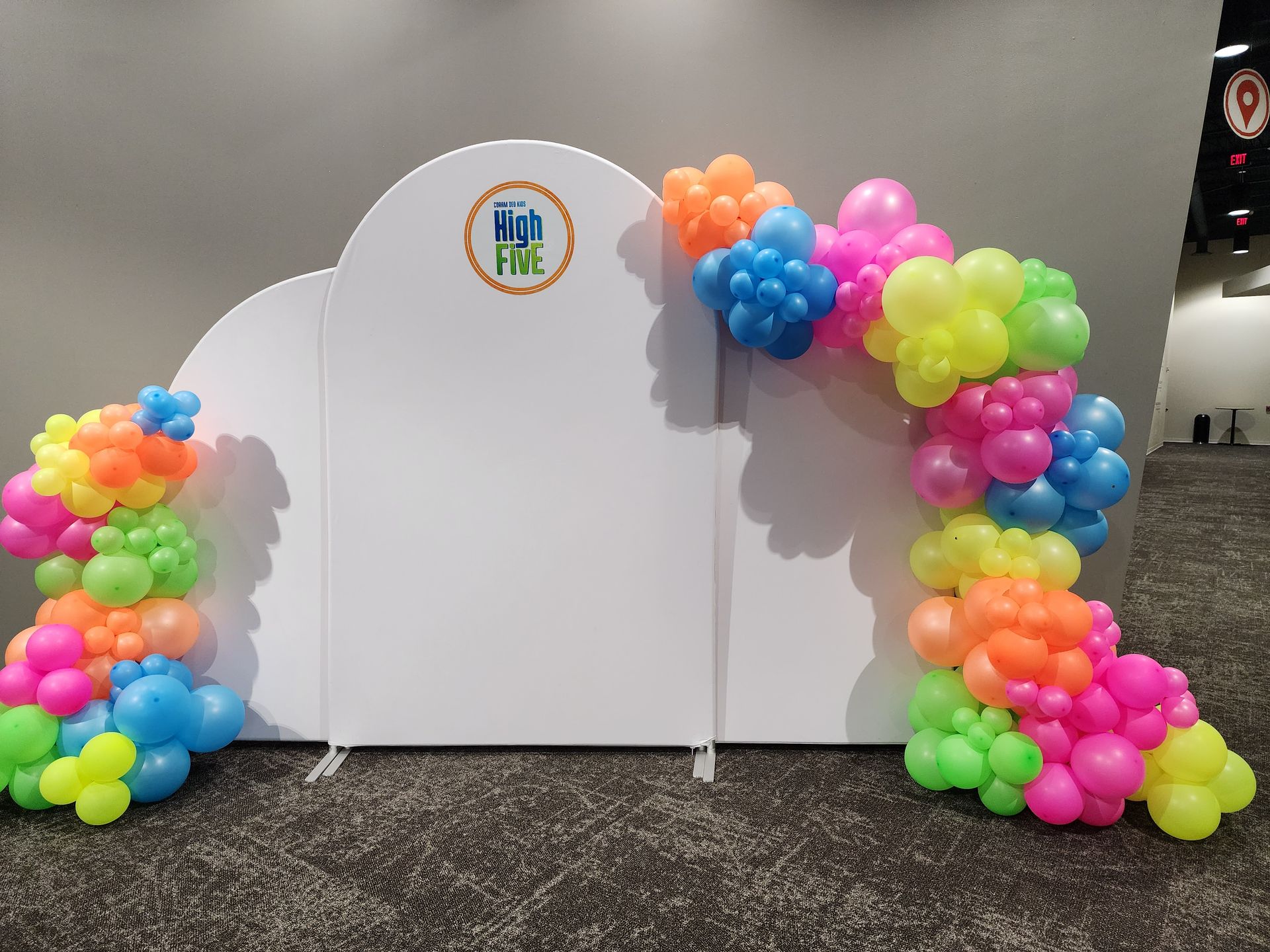 A white wall with a bunch of colorful balloons on it.