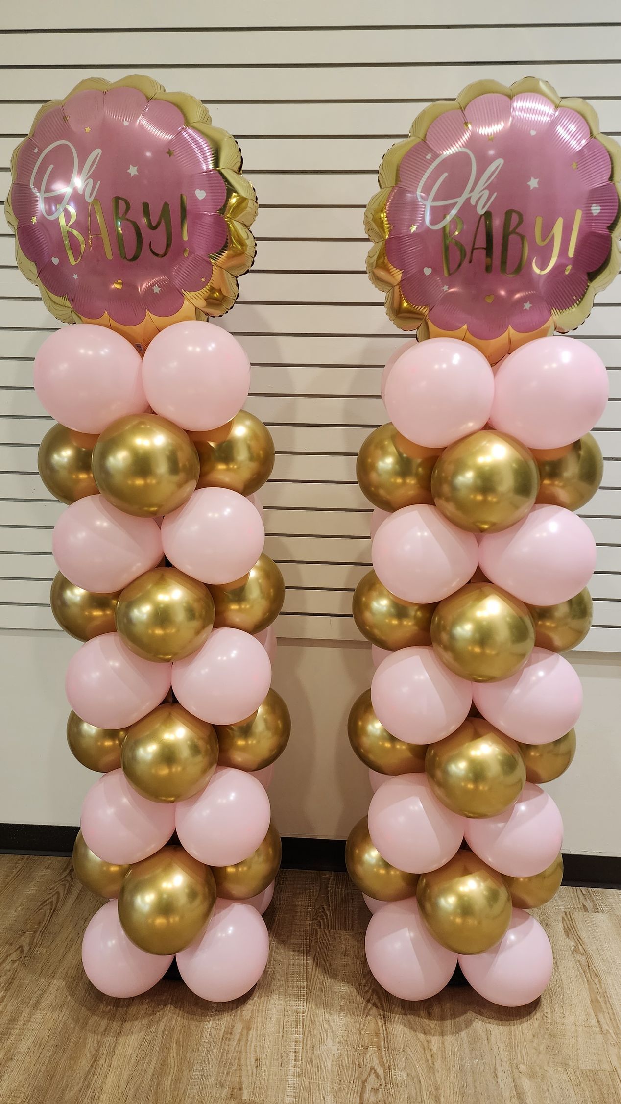 A pair of pink and gold balloon columns for a baby shower.