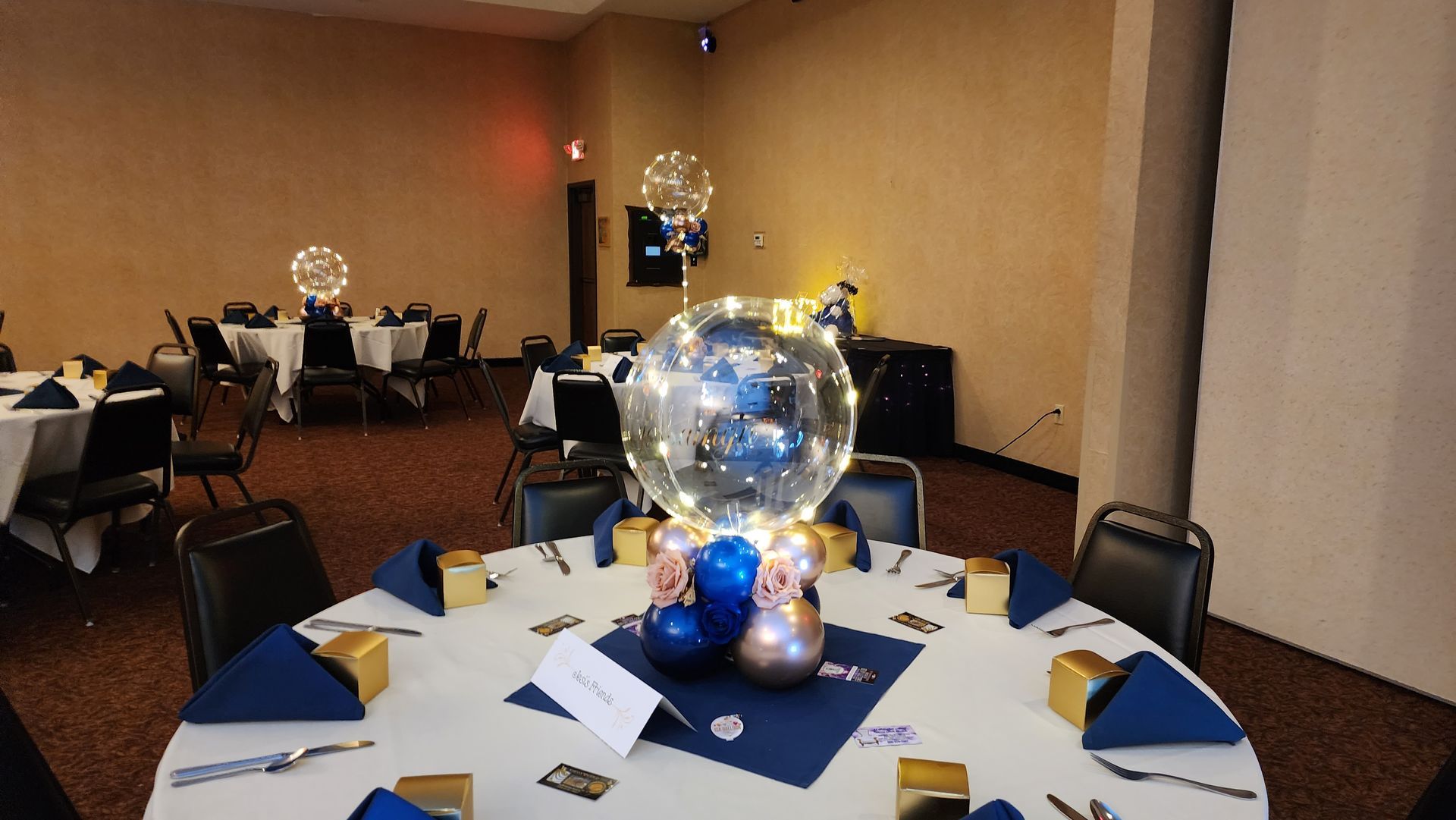 A room with tables and chairs and a balloon in the middle of the table.