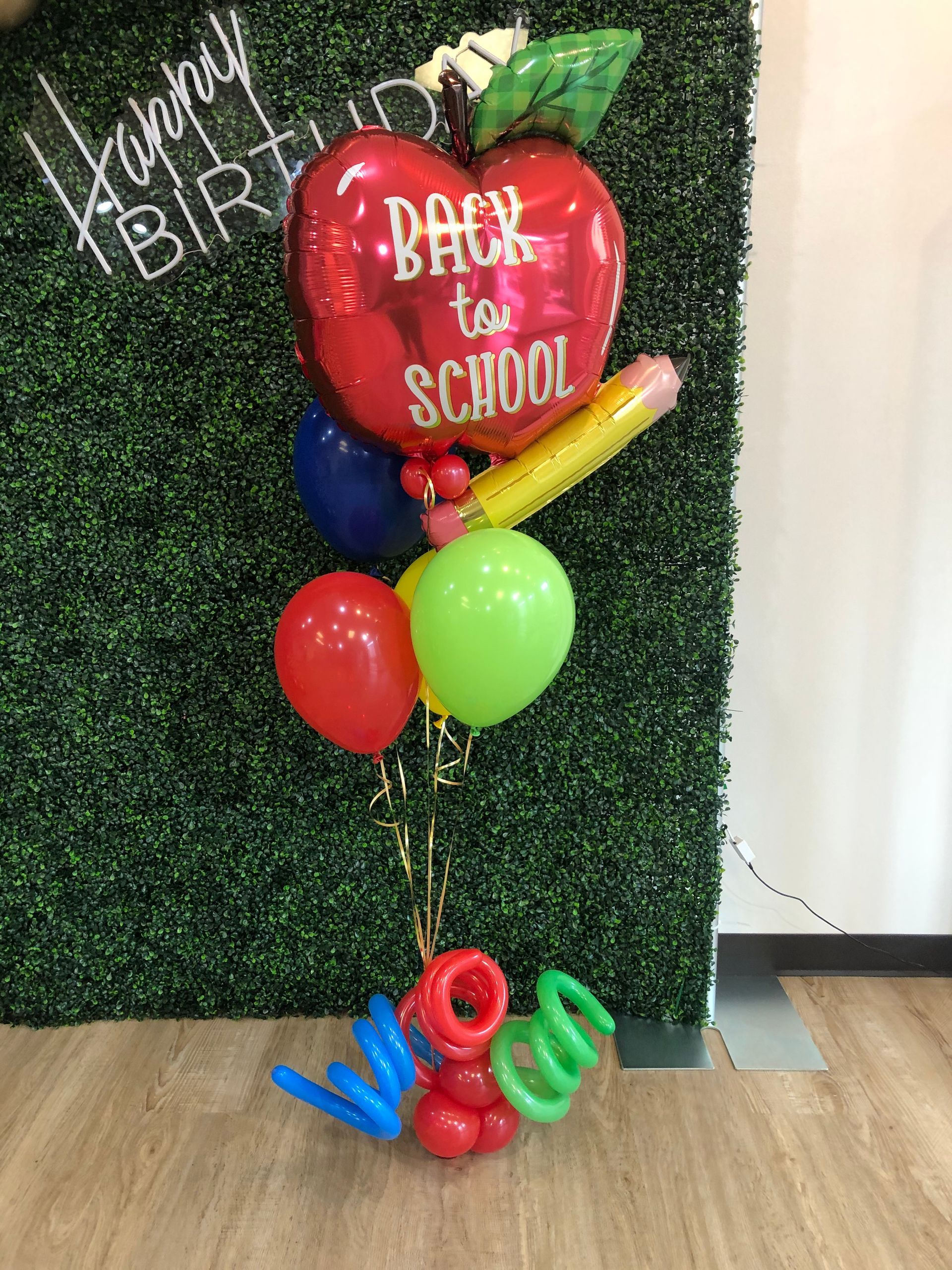 A bunch of balloons in the shape of an apple with the words `` back to school '' written on it.