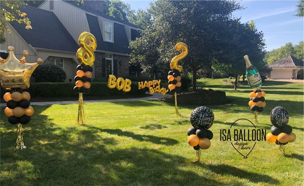 A bunch of balloons are sitting in the grass in front of a house.