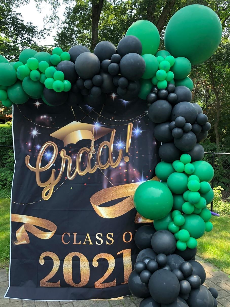 A graduation backdrop with green and black balloons.