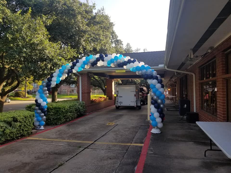 A blue and white balloon arch is in front of a building.