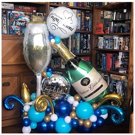 A bottle of champagne is surrounded by balloons in a room.