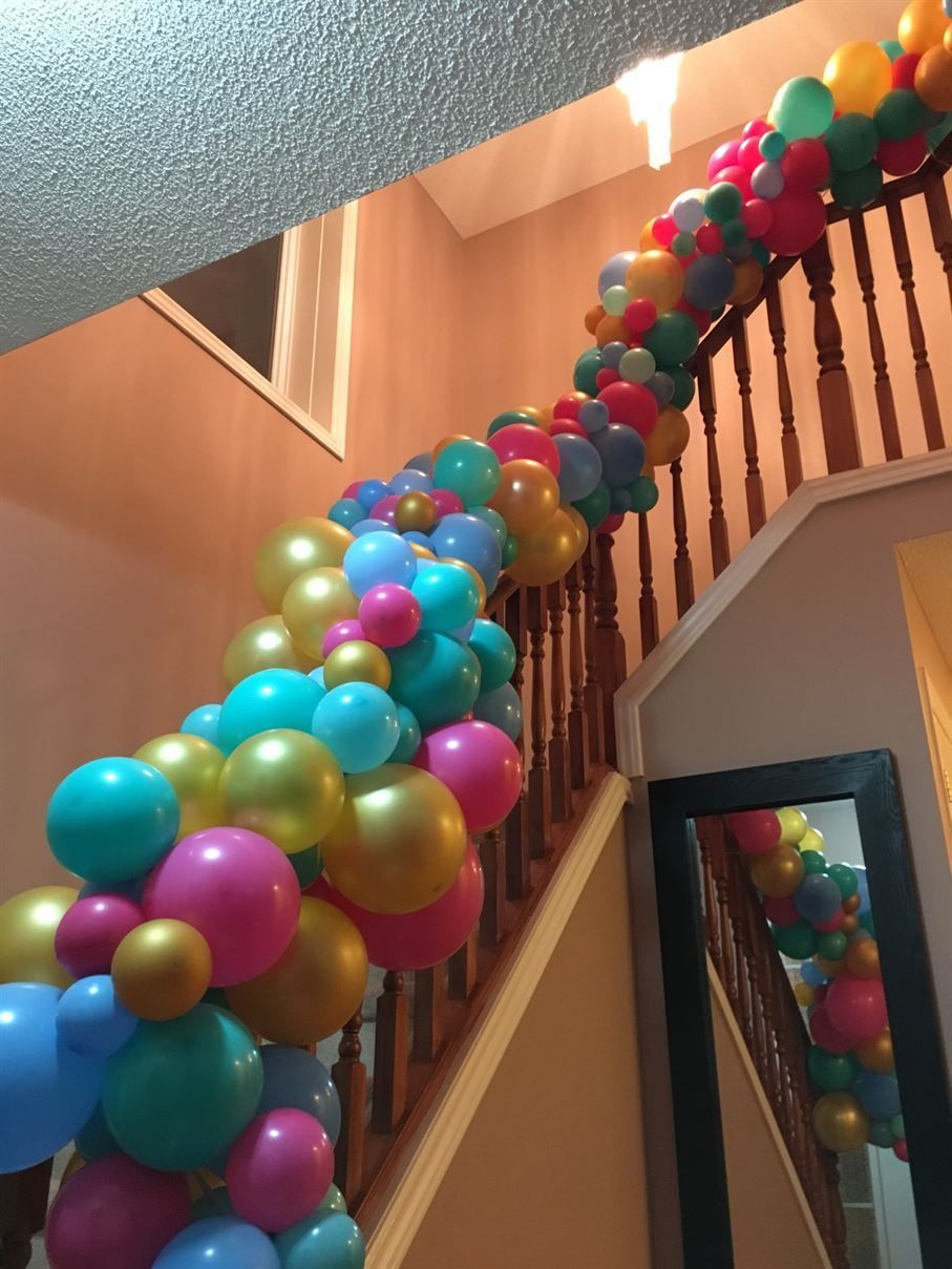 A bunch of colorful balloons are hanging from a staircase